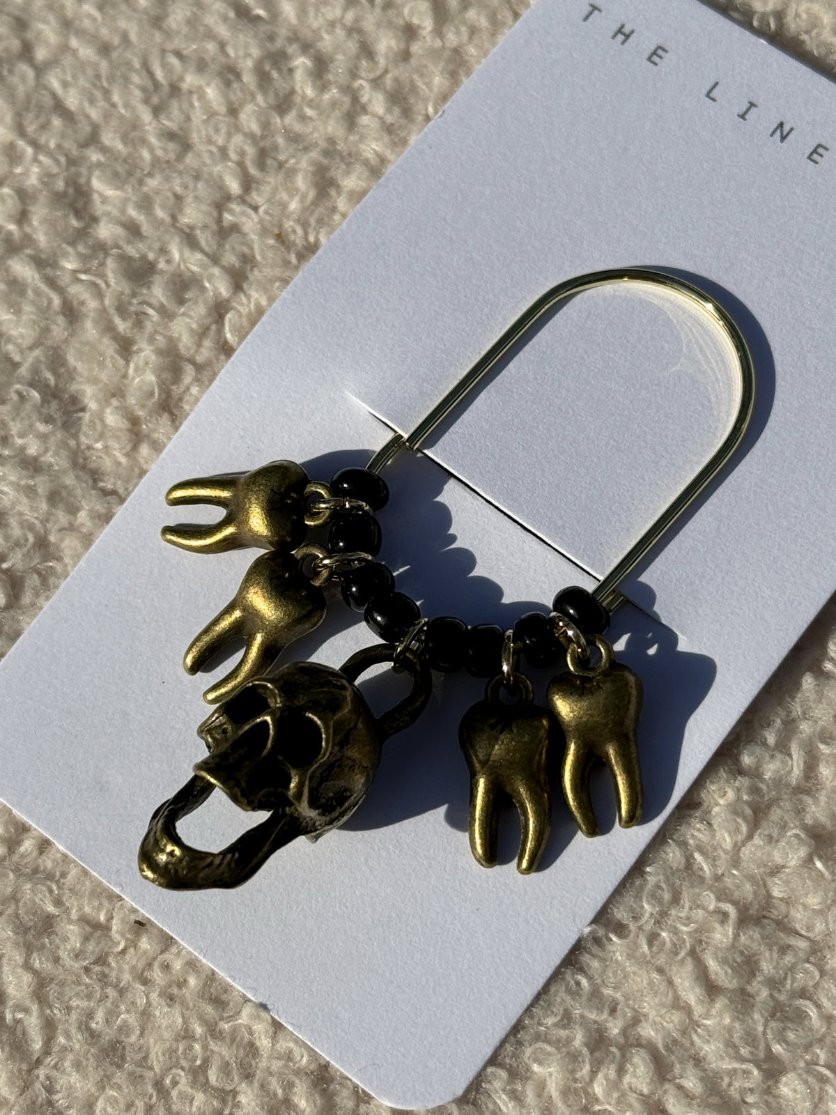 Close-up of the bronze skull and tooth charms on the card