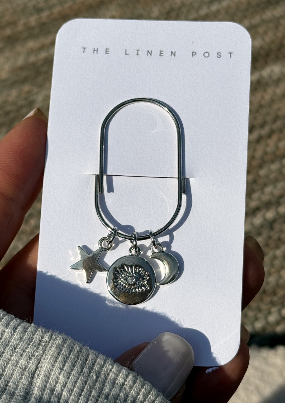 Evil Eye Coin Star & Moon Planner Clip on its card, held in hand